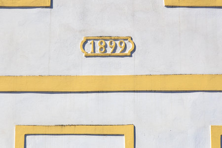 Architectural detail with 1899 date on yellow and white building facade.の写真素材