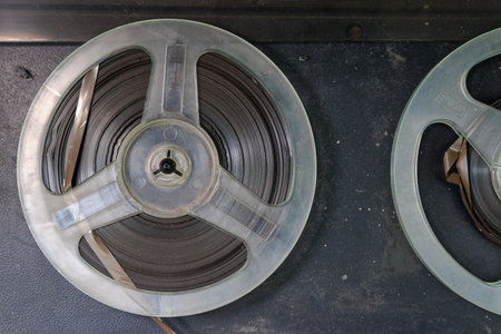 Two old film reels are sitting on a table. The reels are made of plastic and are covered in dust....