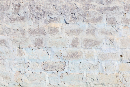 A wall with a white and blue brick pattern. The wall is old and has some cracksの写真素材