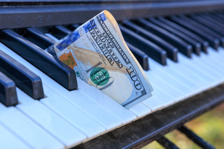 A keyboard with a 100 dollars bill on it. Concept of playfulness and creativity, as the money is not being used for its intended purpose but rather as a prop in a musical settingの写真素材