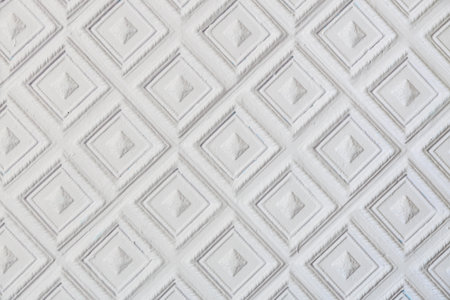 The image is a close up of a white wall with a diamond pattern. The pattern is made up of small squares and triangles. The wall appears to be made of wood and has a very clean and simple designの写真素材