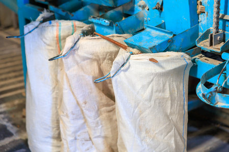 Three bags of white material are hanging from a blue machineの写真素材