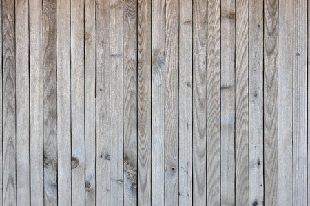 A wooden wall with a grainy texture. The wood is old and worn, but it still has a rustic charm. The wall is bare and unadorned, but it has a sense of warmth and characterの写真素材