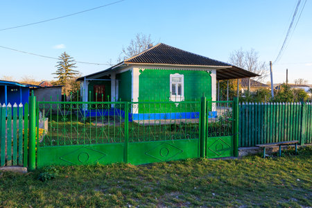 A green house with a blue trim sits in a grassy yardの写真素材