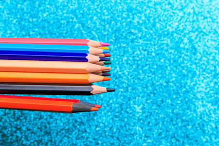Multi-colored pencils on the backdrop with glitter. Background with selective focus and copy space for textの写真素材