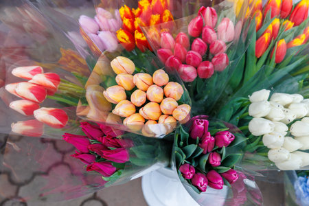 A bouquet of flowers in a white vase with a plastic covering. The flowers are of different colors and sizes, including pink, orange, and white. The arrangement is beautiful and vibrantの写真素材