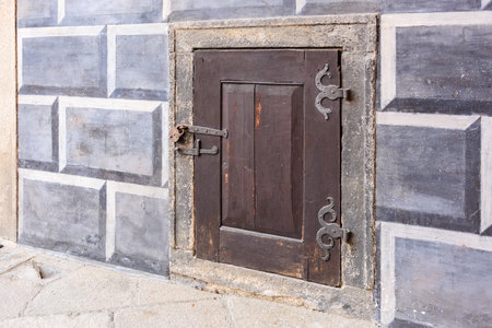 Rustic wooden cellar door with stone frame and intricate metal hinges.の写真素材