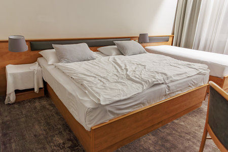 Modern hotel room with double bed and white linens featuring minimalist decor.の写真素材