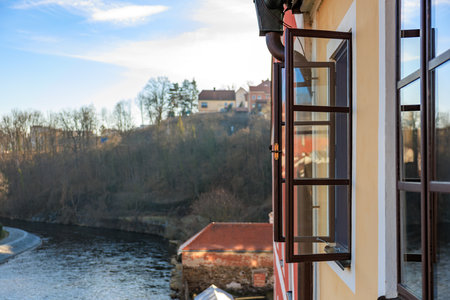 A window on a building overlooking a river. The window is open and the view is of a city with a river running through itの写真素材