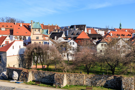 A small town with a stone wall and a green roof. The houses are white and red. The sky is blue and clearの写真素材