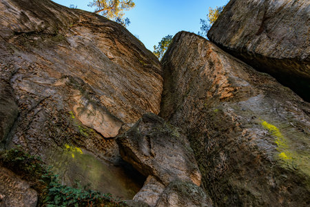 Massive natural rock formation with texture and green moss in bright sunlight.の写真素材