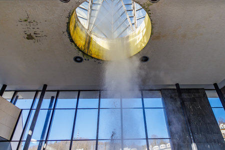 Water leakage through skylight in modern building interior with large windows, natural geyser.