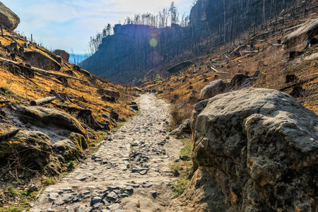 Rocky path through barren mountains in early spring with bright sky.の写真素材