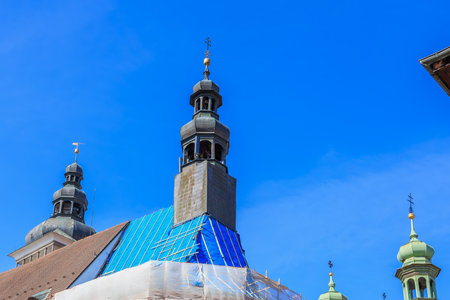 Historic church under renovation with blue protective covering and tall spires against clear sky.の写真素材