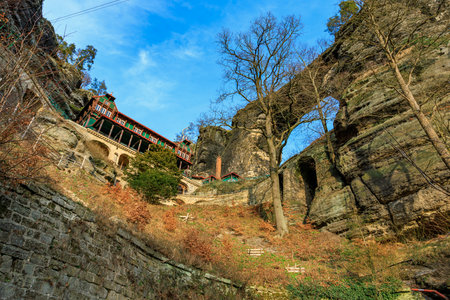 Picturesque mountain lodge below natural rock arch with clear blue sky.の写真素材