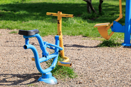 Outdoor public fitness area with colorful exercise machines on gravel surface.の写真素材