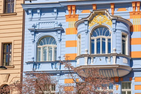 Colorful blue and orange art nouveau building facade with cherry blossoms.の写真素材