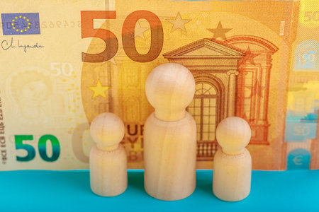 Wooden figures with euro currency background representing economic concepts.の写真素材
