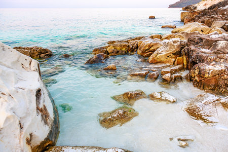 A rocky beach with a body of water in front of it. The water is clear and calmの写真素材