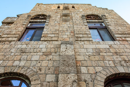 Historic stone building facade with arched windows against blue sky.の写真素材