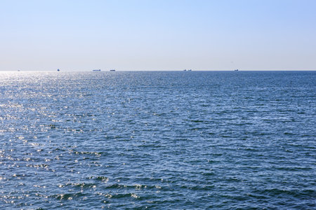 Calm ocean horizon with distant ships under clear blue sky.の写真素材