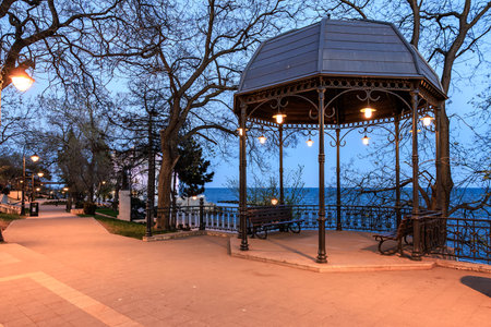 Evening view of oceanfront gazebo with benches and streetlights.の写真素材