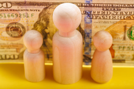 Wooden figures of family with us dollar bill background.の写真素材