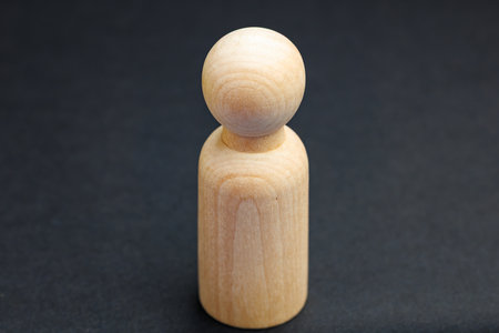 Minimalist wooden figurine on dark background.