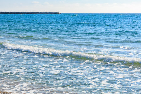 Scenic beach waves on a sunny day with clear blue water and sky.