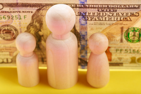 Wooden figures and us dollar conceptual image depicting economy and family.の写真素材
