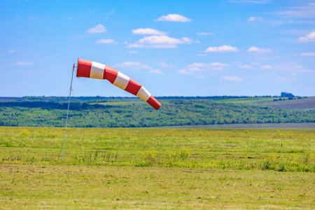Red and white windsock on clear day at open field.の写真素材