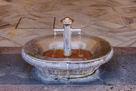 Ornate metal fountain with dual streams in public stone setting.の写真素材