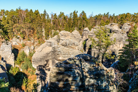 Majestic rock formations in dense forest landscape under clear blue sky.の写真素材