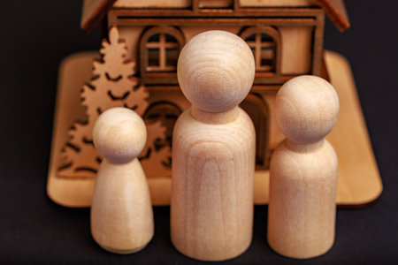 Wooden figures of family with house on black background.の写真素材