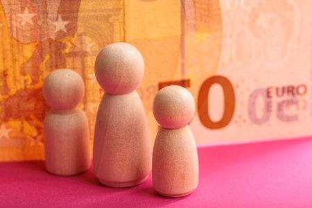 Wooden figures on pink background with euro banknote in financial concept.の写真素材