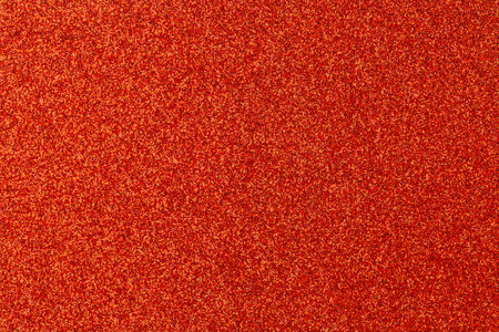 A close up of a red background with many orange dots scattered throughout. The red background is the dominant color of the image, while the orange dots are smaller and more numerousの写真素材