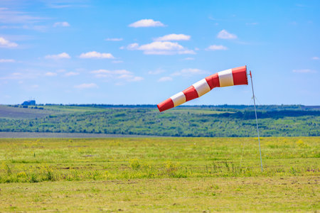 Red and white windsock in open field on sunny day.の写真素材
