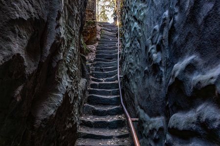 Stone stairway through narrow rocky passage with metal handrail.