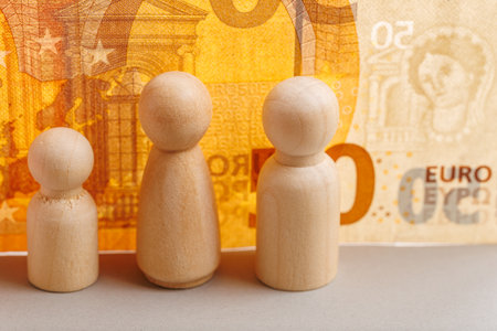 Wooden figures with euro banknote backdrop representing economic growth concept.の写真素材