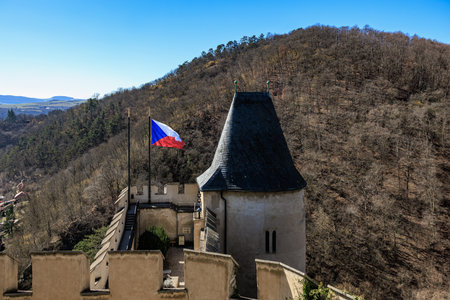 Czech castle tower with national flag in scenic mountainous landscape.の写真素材