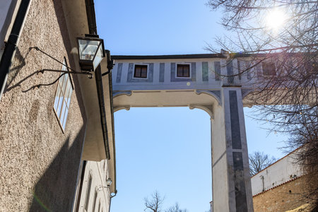Historic archway and buildings under clear blue sky.の写真素材