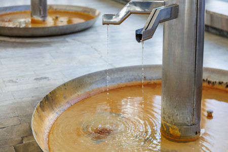 Mineral water fountain with metal spouts in bathhouse interior.の写真素材