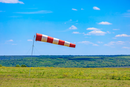 Striped windsock indicating direction on clear day in open field.の写真素材