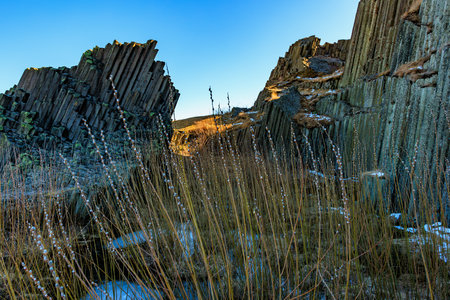Majestic basalt columns in scenic geologic landscape under clear blue sky.