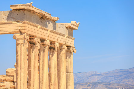 The columns are made of stone and are part of a building. The sky is blue and the sun is shining, Acropolis in Athensの写真素材