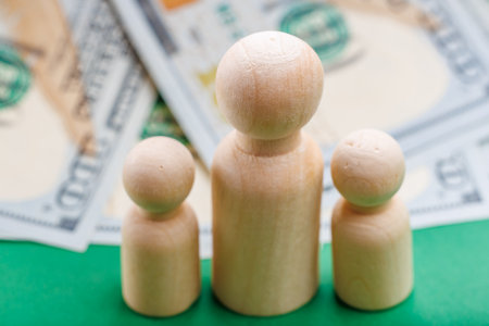 Wooden figures representing family with us dollar currency background.の写真素材