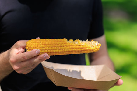 Male enjoying fresh corn on a sunny day.の写真素材