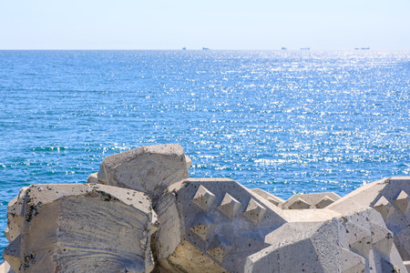 Sparkling ocean horizon with geometric concrete breakwaters on a sunny day.の写真素材