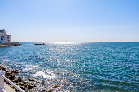 Sparkling blue sea with rocky shoreline on sunny day.の写真素材