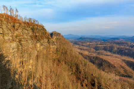 Scenic view of rocky cliff and vast valley under clear sky at sunset.の写真素材